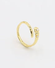 Close-up of an open gold-plated 925 sterling silver ring with a hammered texture and three delicate zirconia stones, handcrafted and photographed on a white background – minimalist Swiss jewelry design.