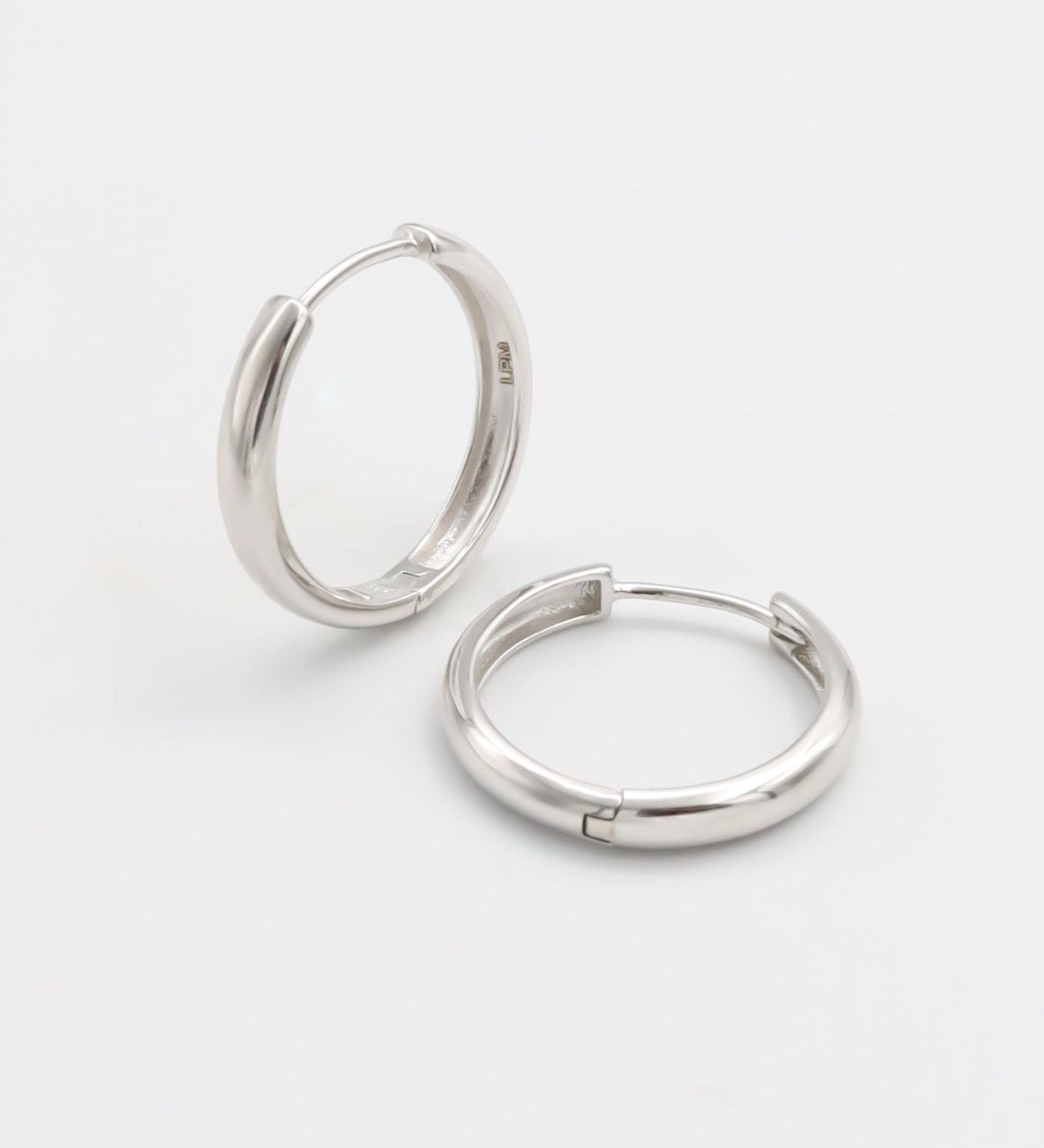 A pair of silver hoop earrings with a hinged clasp, displayed on a white background.
