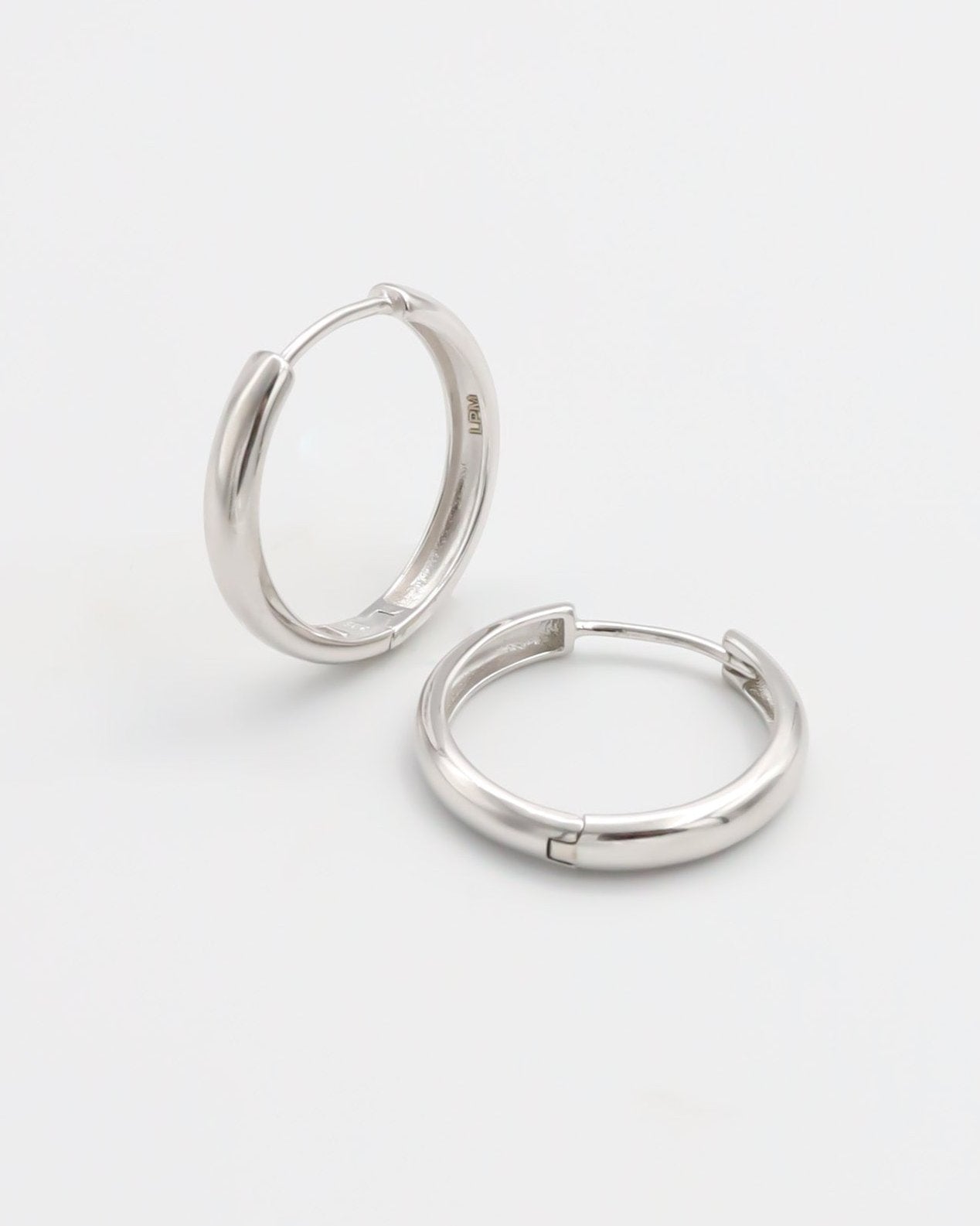 A pair of silver hoop earrings with a hinged clasp, displayed on a white background.