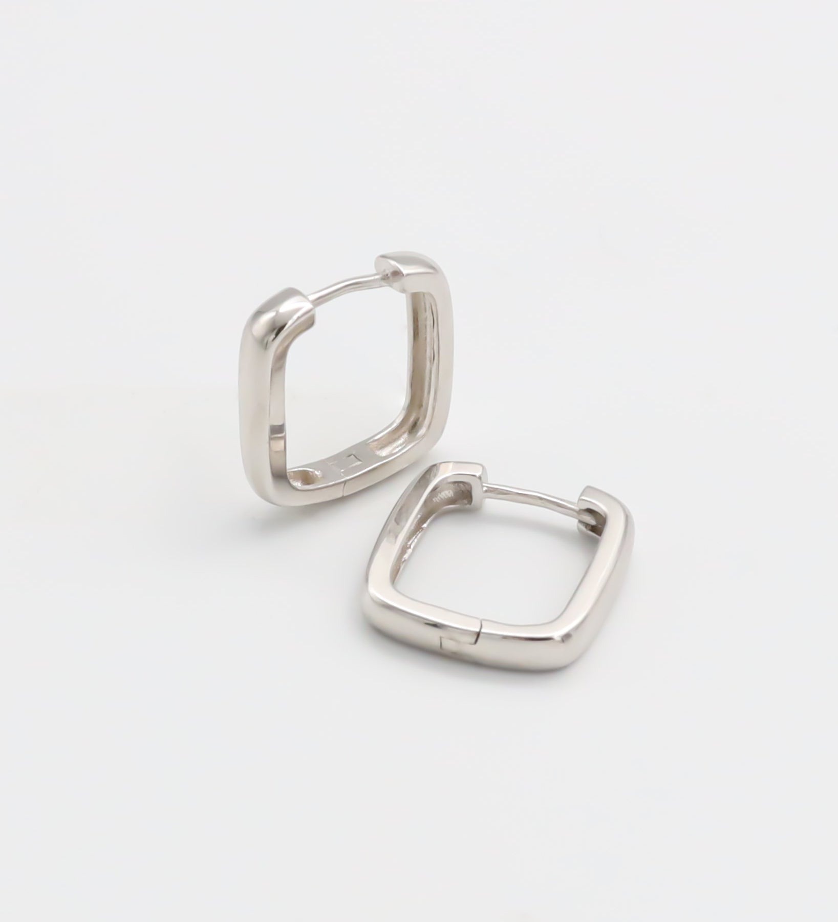 A pair of silver-colored hoop earrings with a hinged clasp, displayed against a white background.