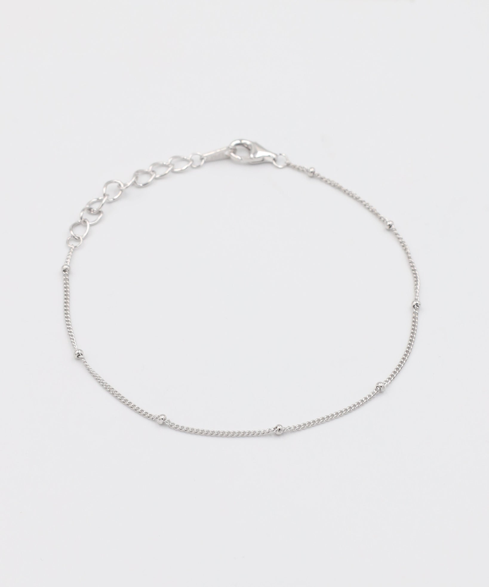 A silver bracelet with small spherical embellishments, displayed against a white background.