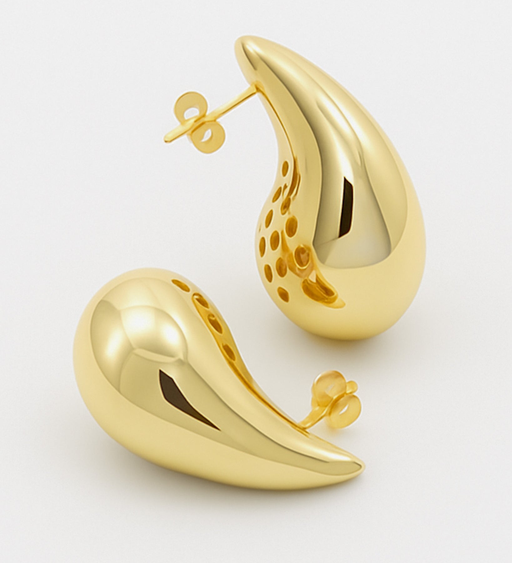 Gold earrings on a light gray background