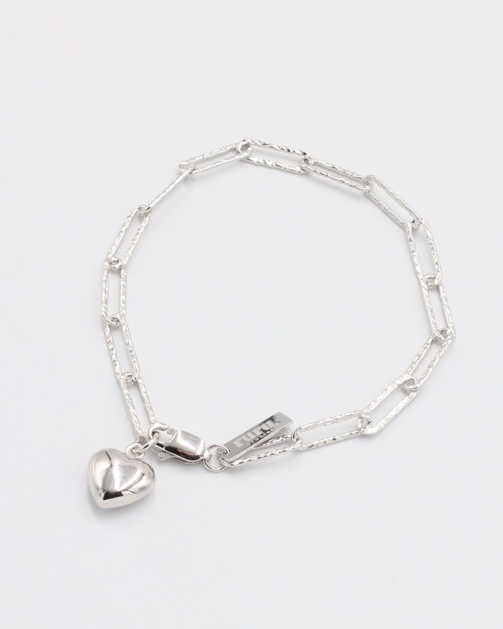 A silver bracelet with a heart-shaped charm on a white background.
