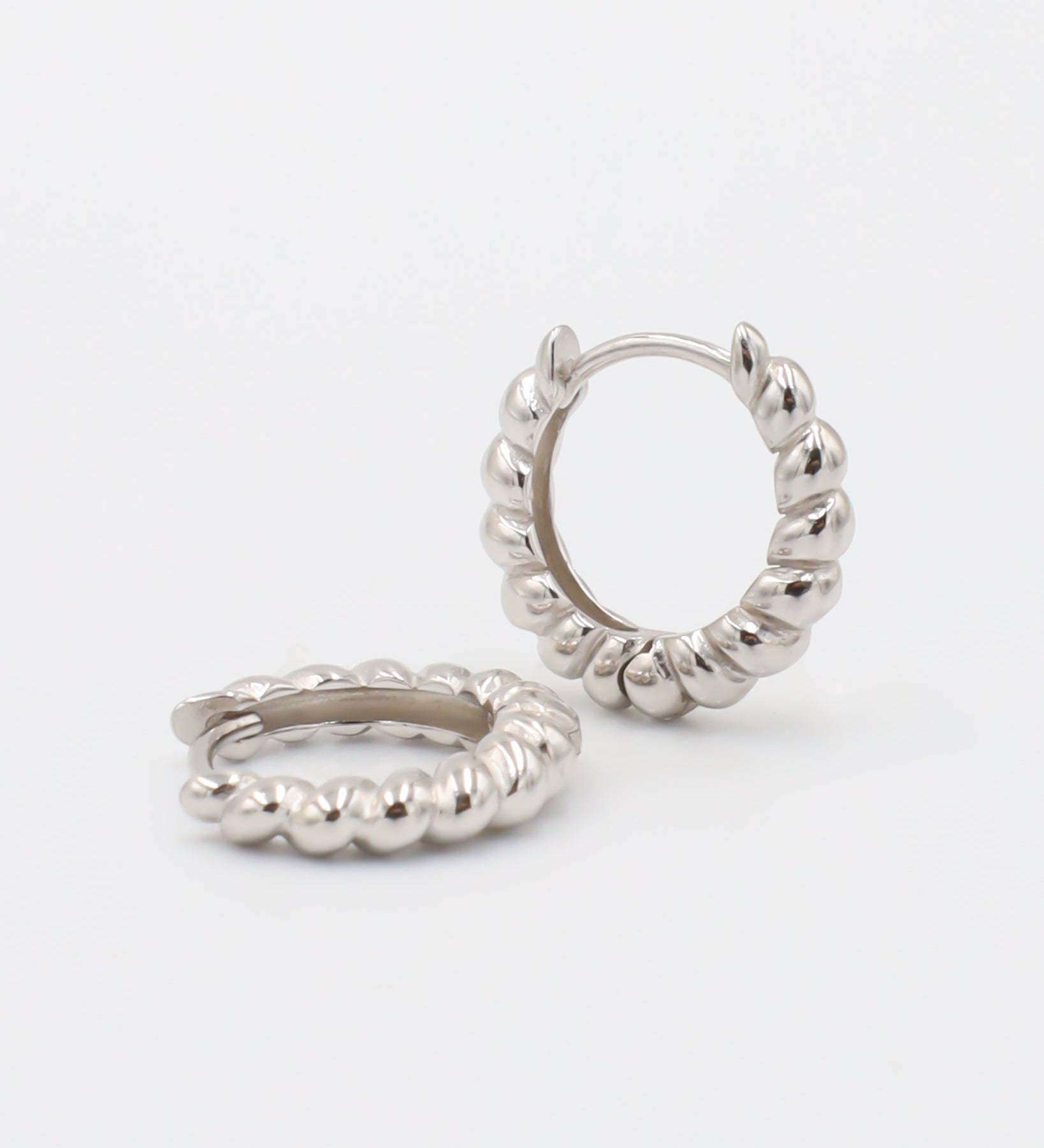 A pair of silver hoop earrings with a hinged clasp, displayed against a white background.