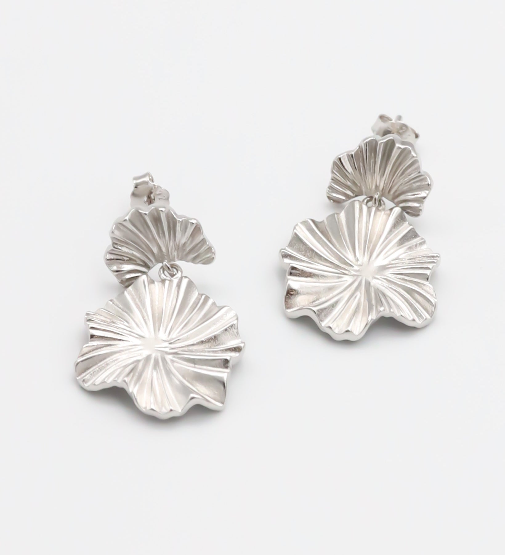 A pair of silver stud earrings with a butterfly clasp and floral design