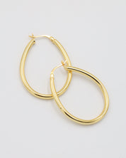 A pair of gold creole earrings with a latch back clasp on a white background.