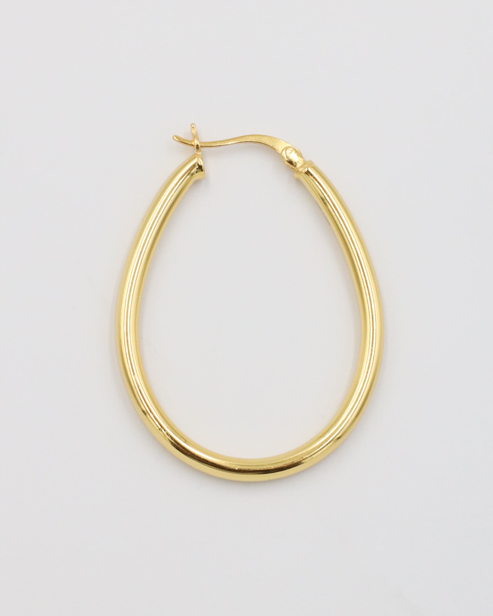 A single gold creole earring with a latch back clasp on a white background.