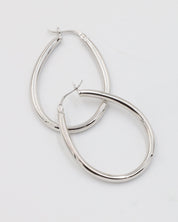 A pair of silver creole earrings with a latch back clasp on a white background.