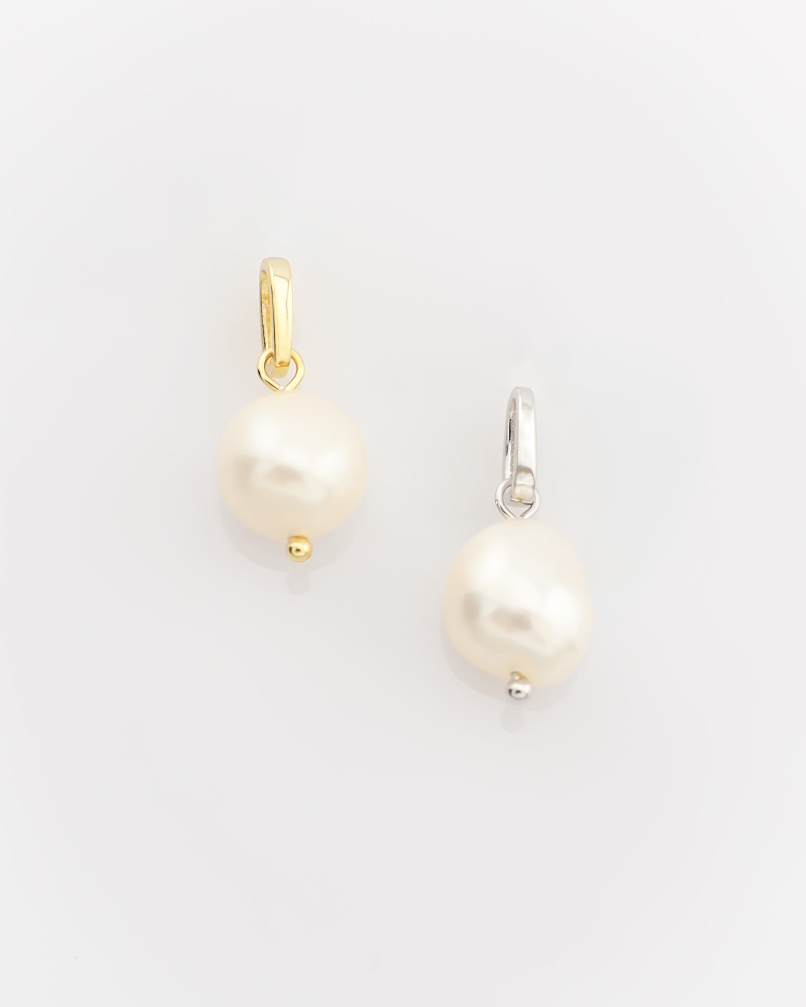 Two pearl earrings on a light gray background