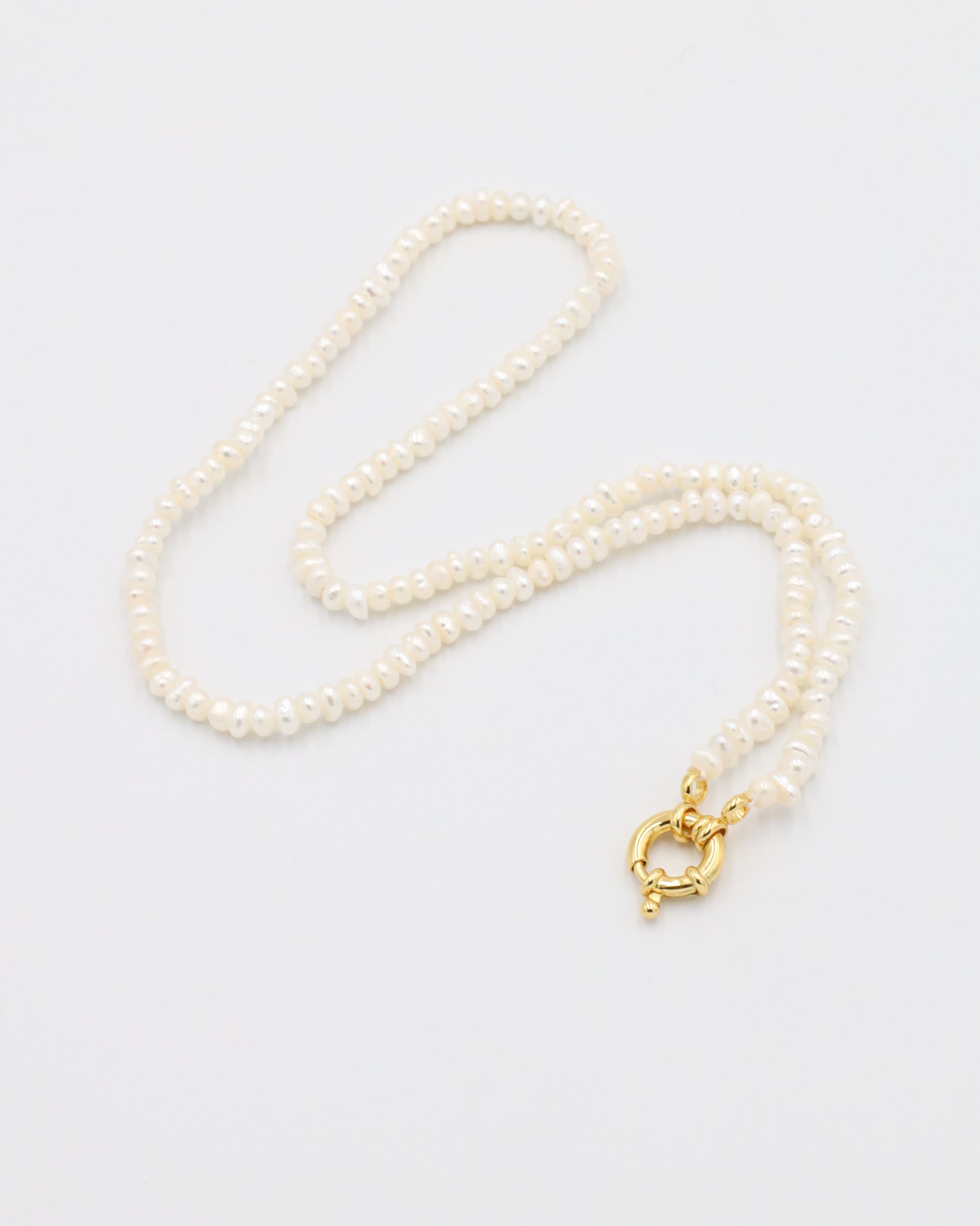A white pearl necklace with a gold clasp on a white background.