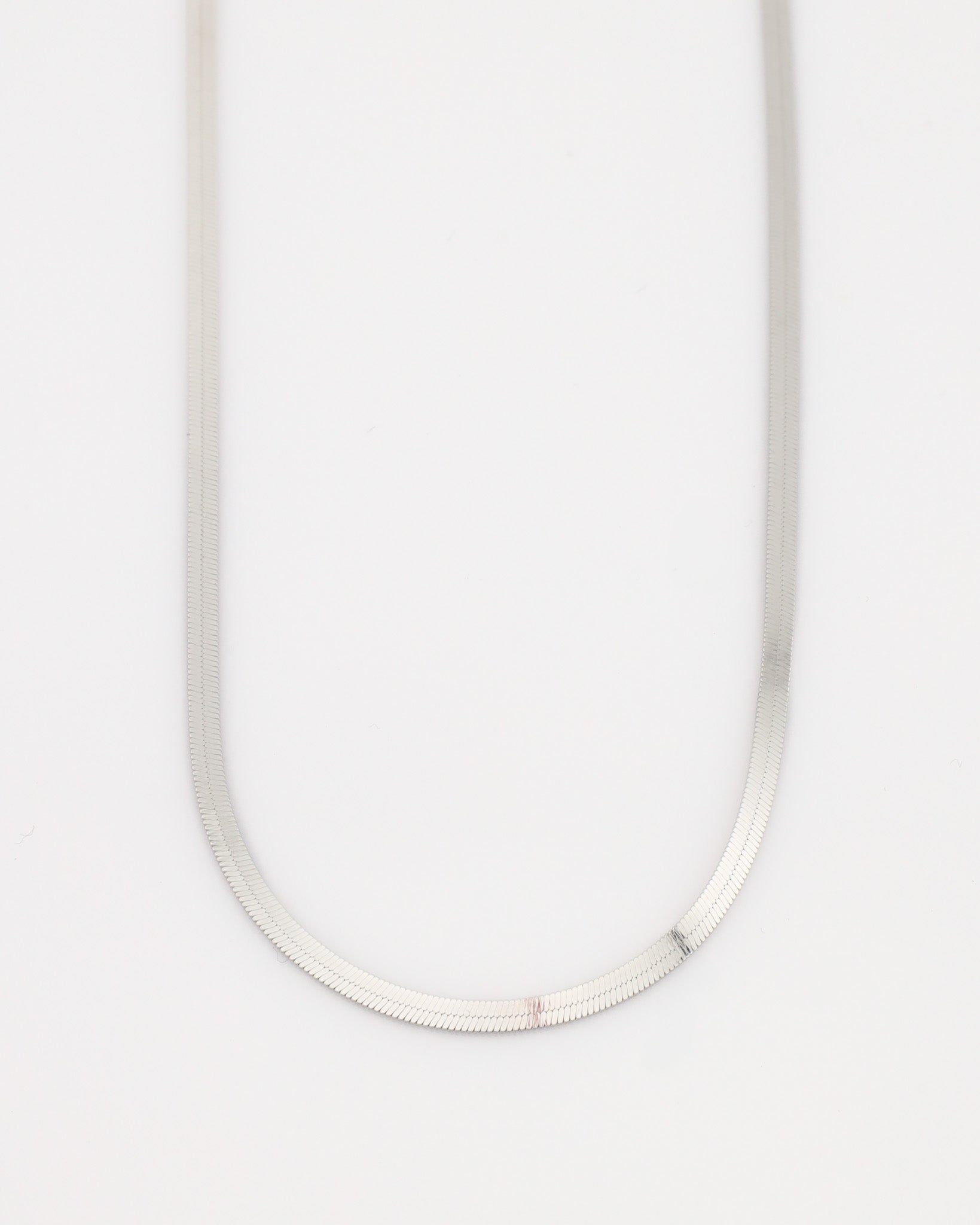 Silver necklace on a light gray background