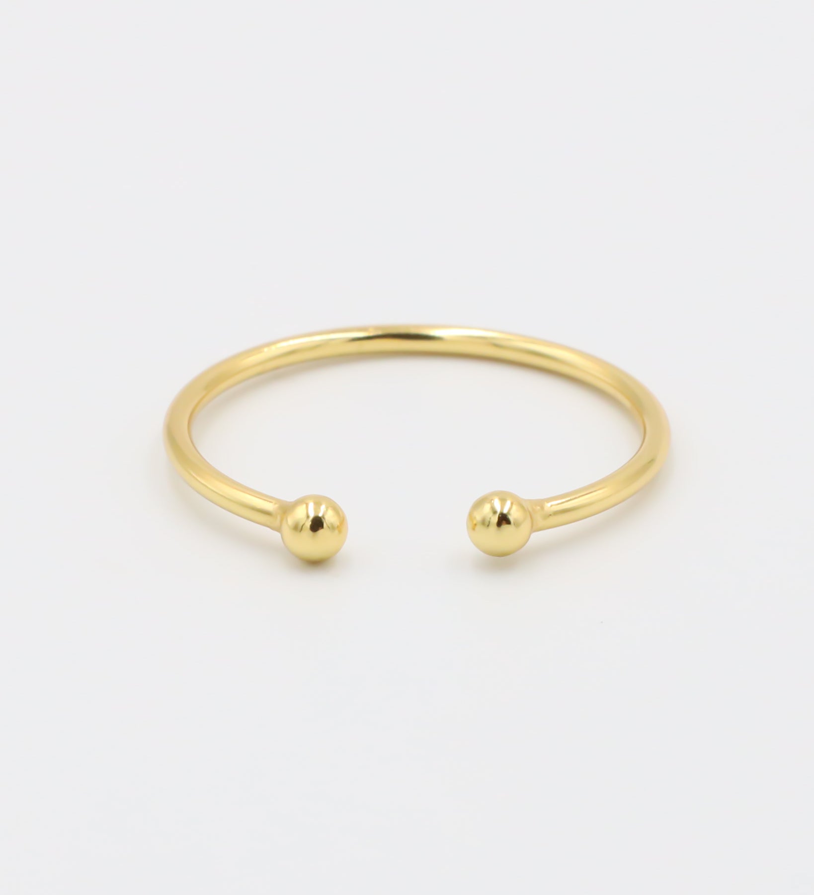 A simple gold-colored ring with two spherical decorations, displayed against a white background.