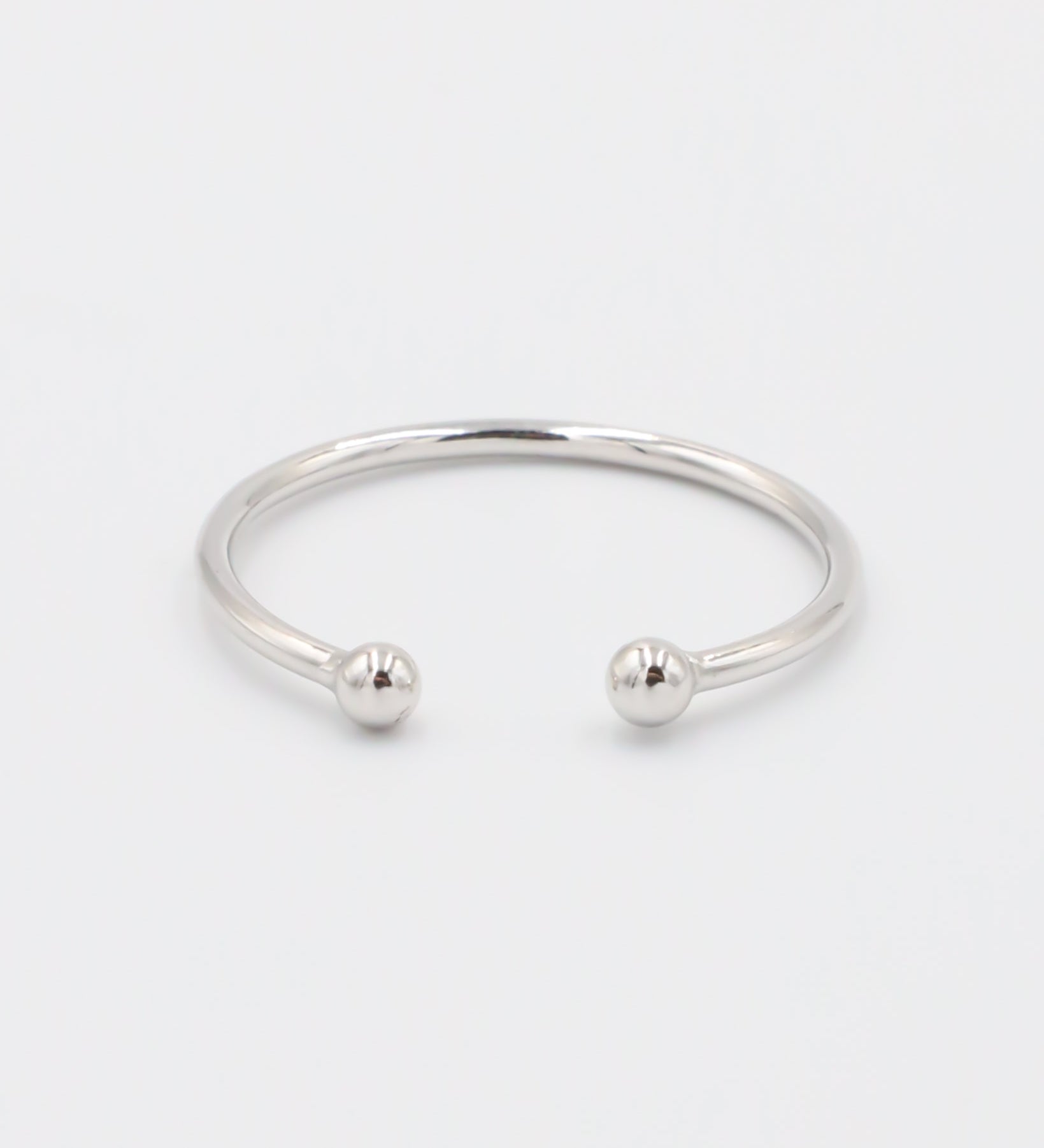 A simple silver bracelet with an adjustable band and small spherical embellishments at the ends.