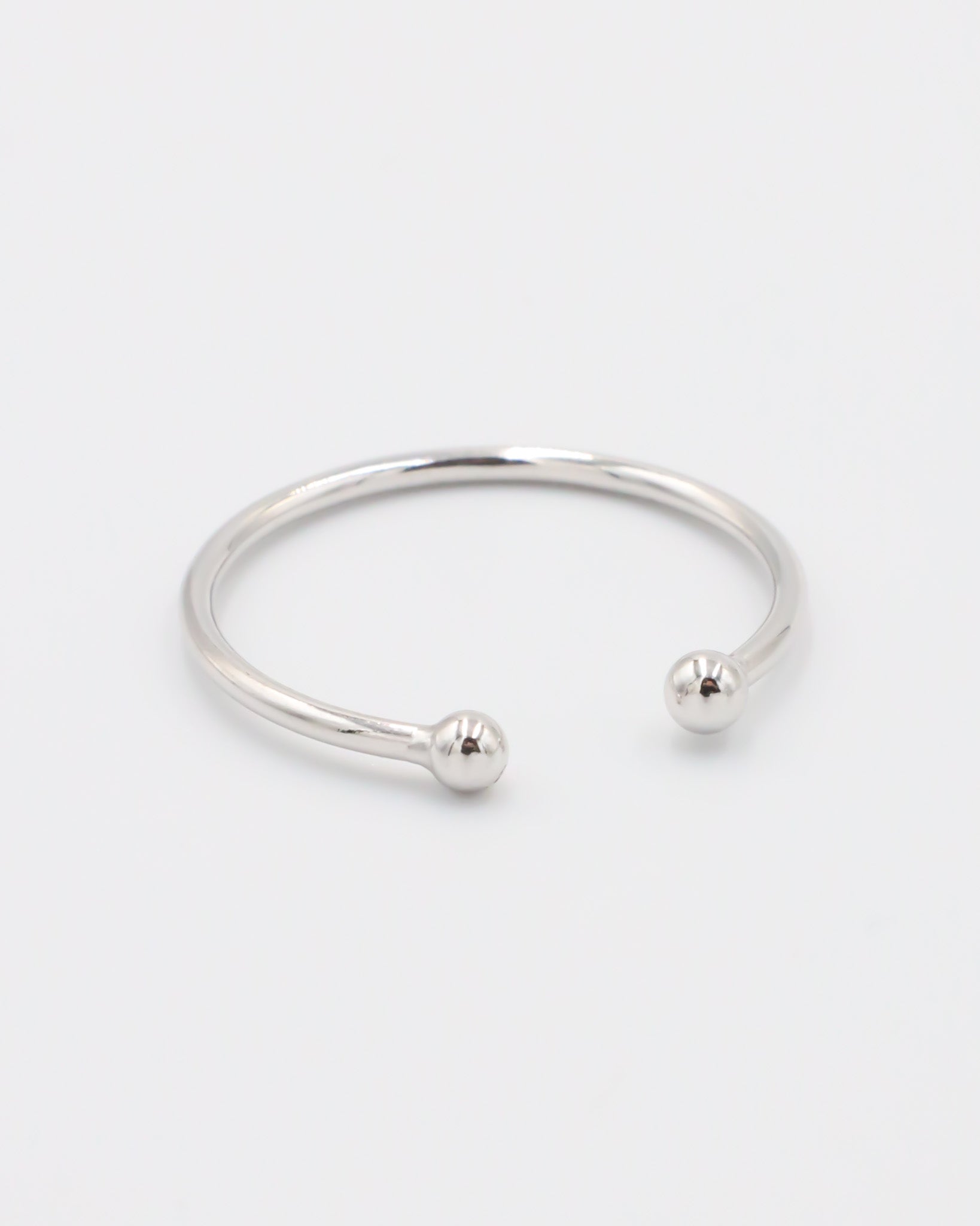 A simple silver bracelet with an adjustable band and small spherical embellishments at the ends.