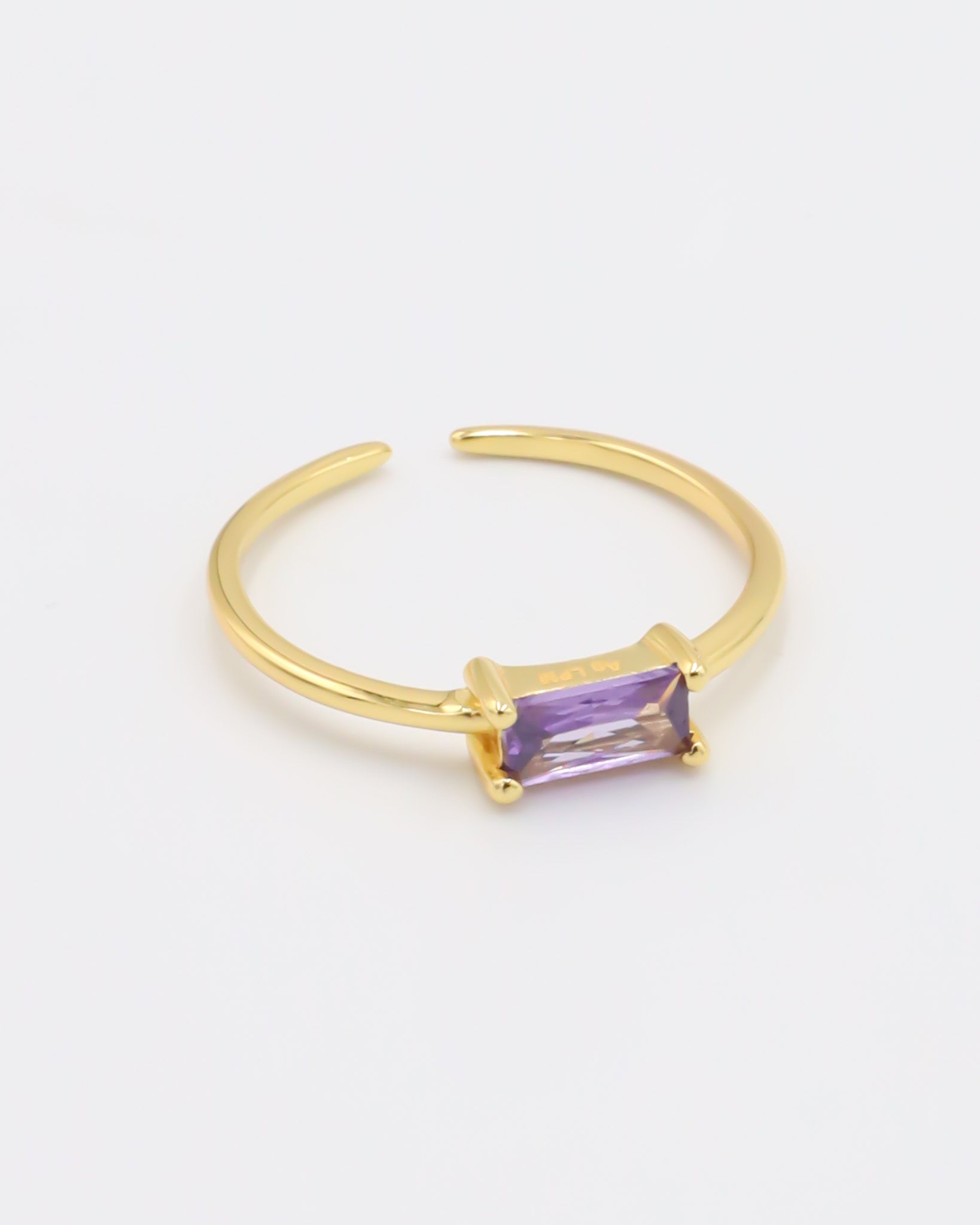 A gold-colored ring with an adjustable band and a rectangular purple gemstone.