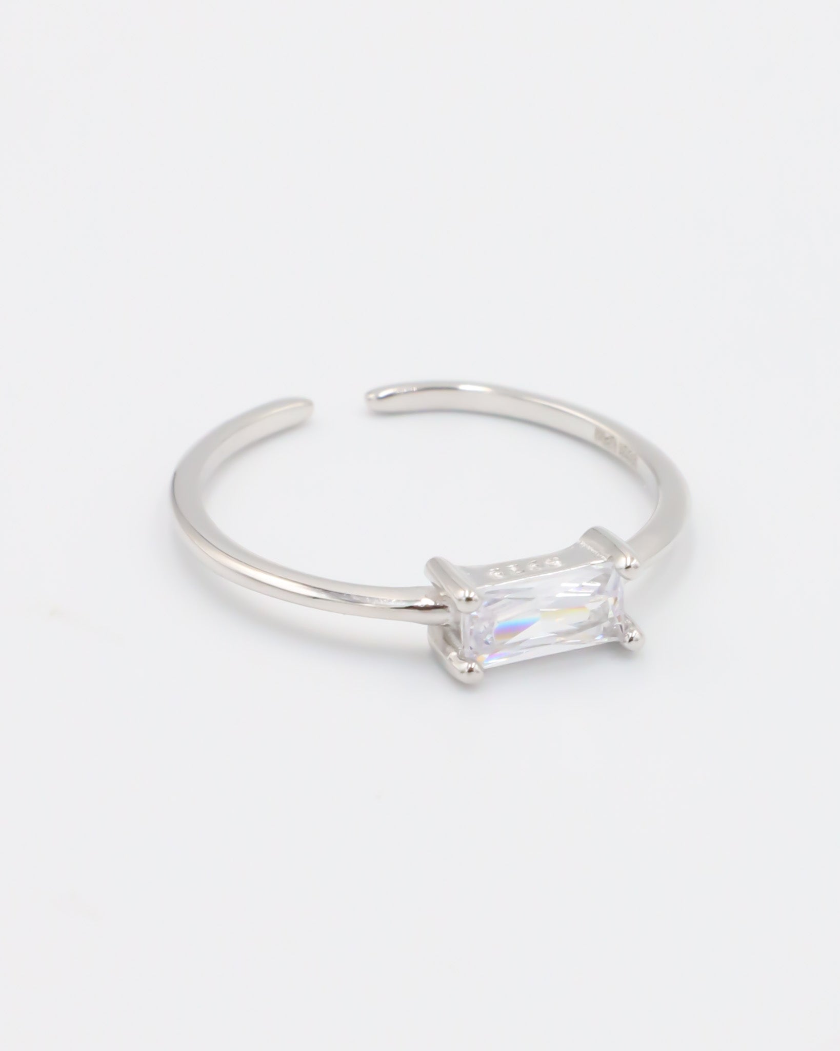 An adjustable silver ring with a clear central stone, on a white background.