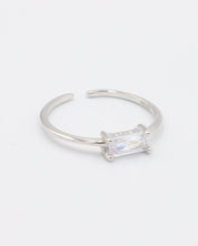 An adjustable silver ring with a clear central stone, on a white background.