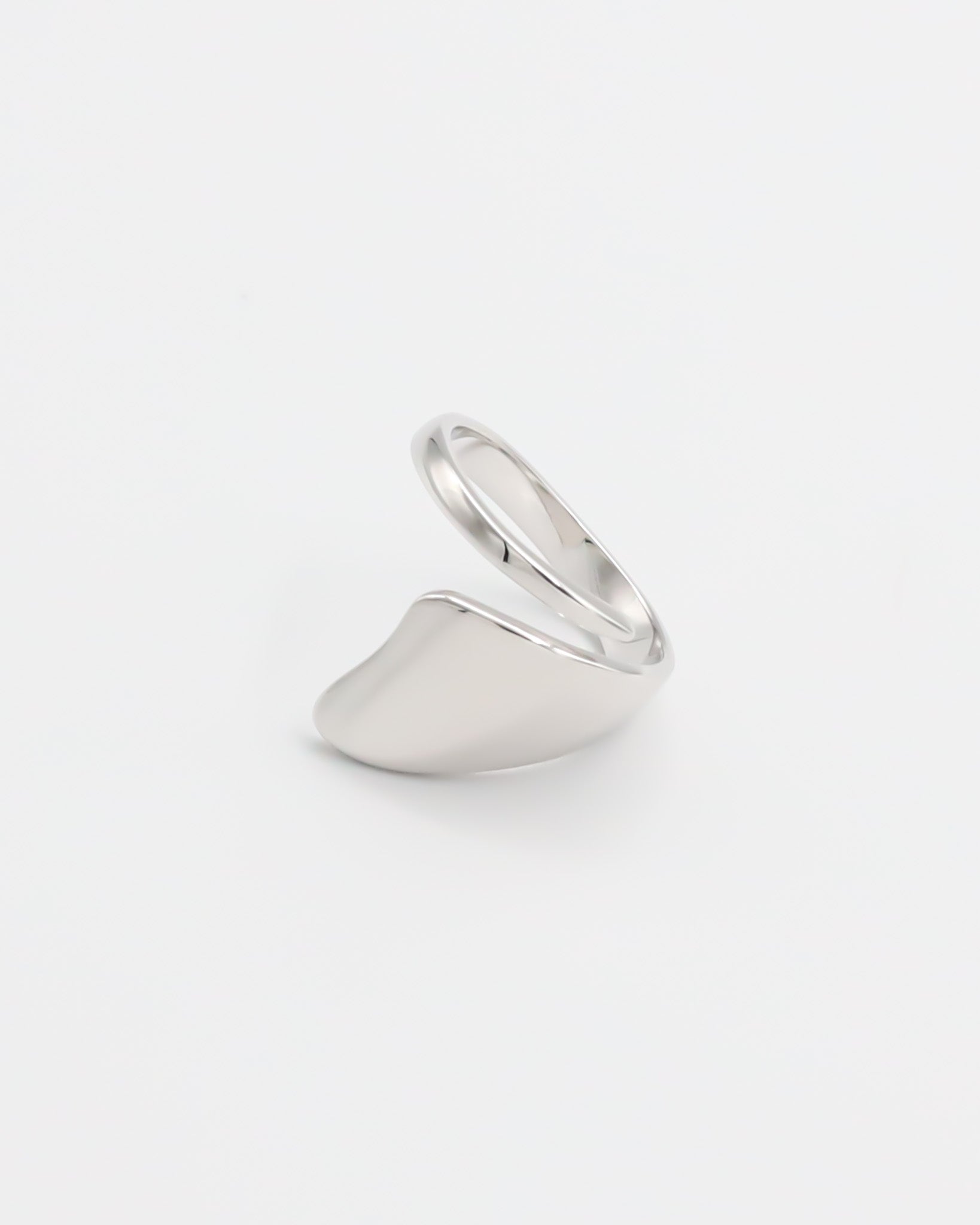 A silver ring with an abstract design on a white background.