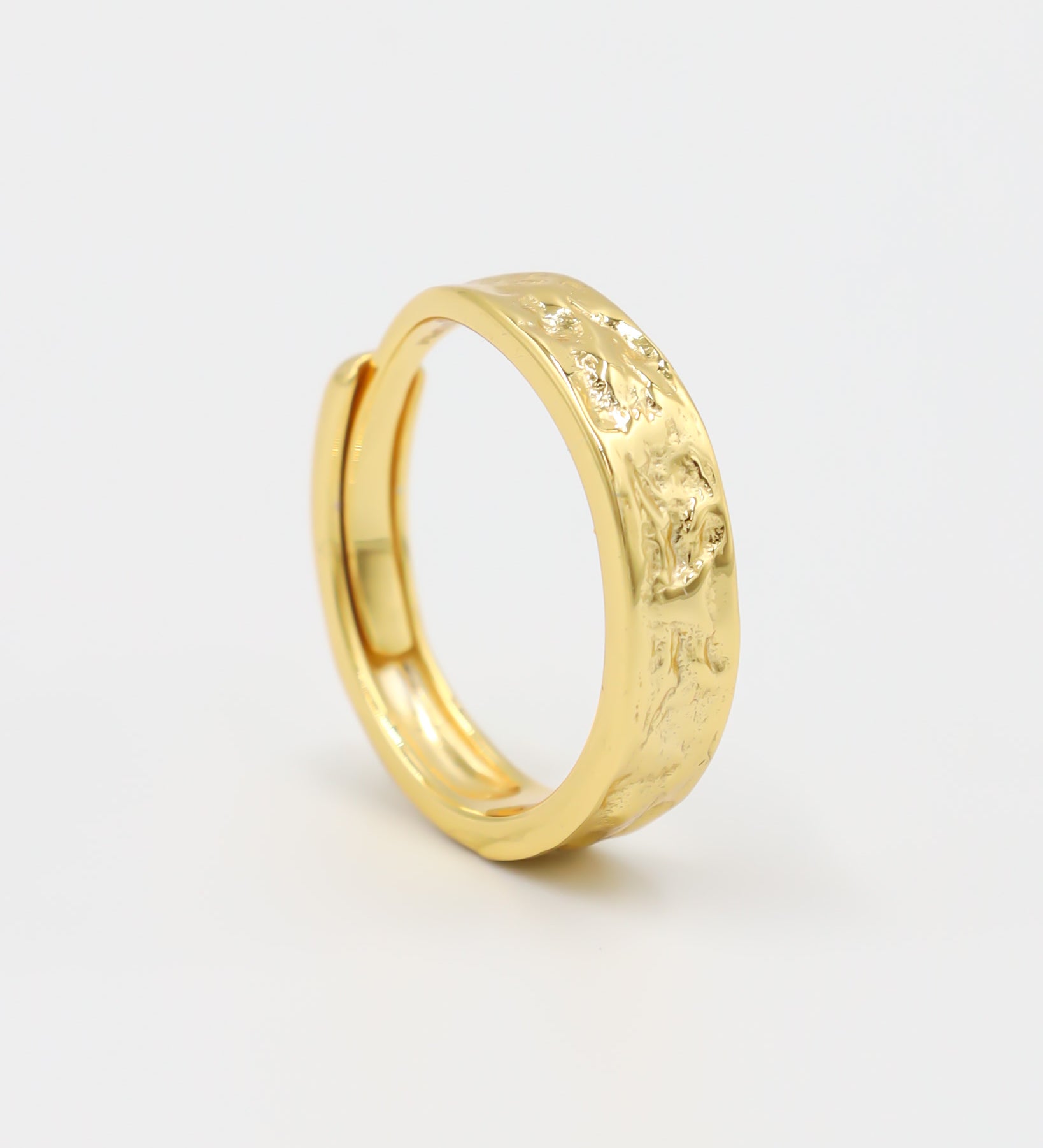 A gold-colored ring with intricate designs on the top surface, displayed against a white background.