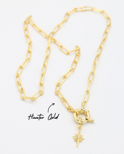 Gold star-shaped pendant with a zirconia stone, paired with a chain necklace.