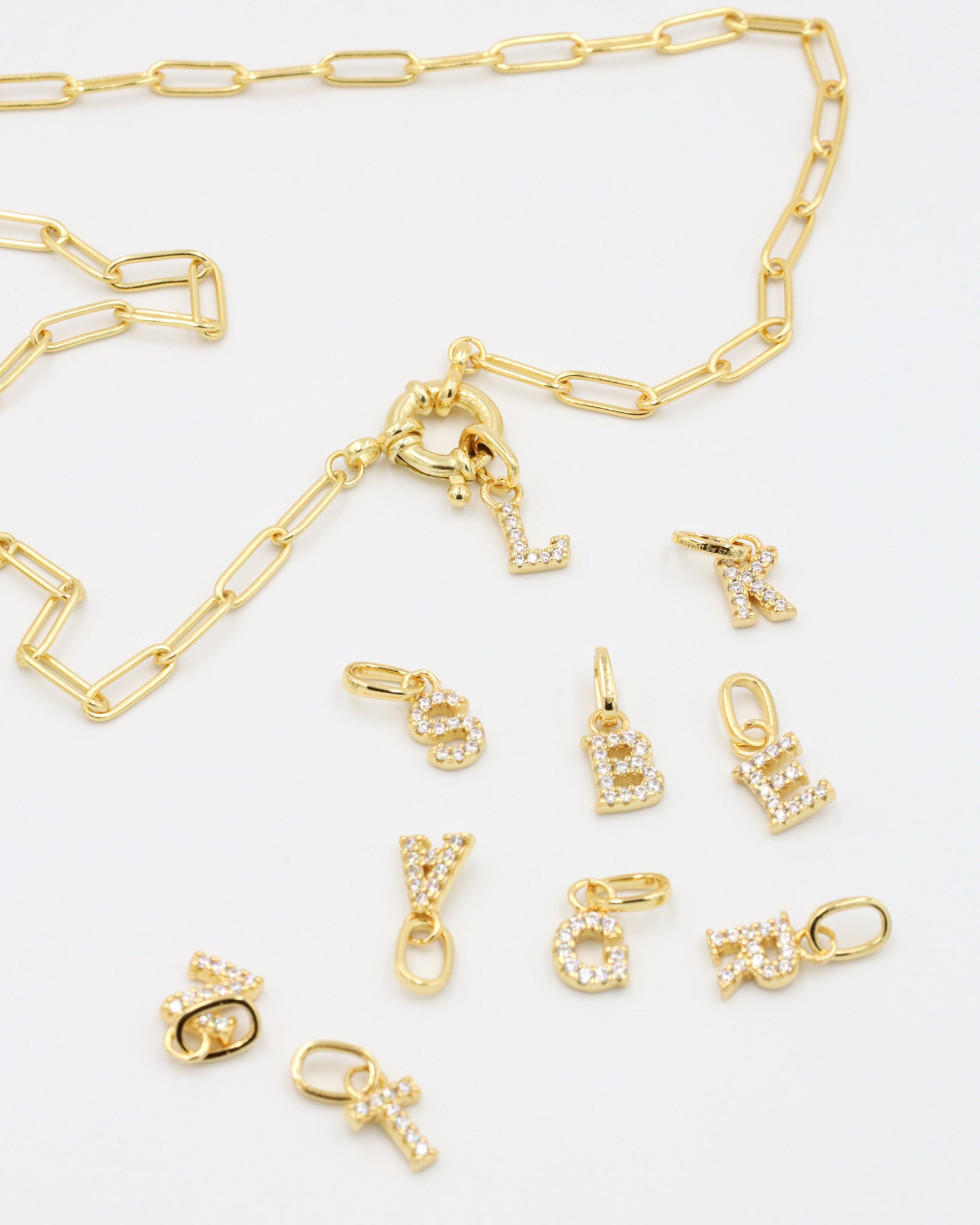 Gold chain with detachable letter pendants, showcasing the mix-and-match versatility of the gold-plated letter charms.