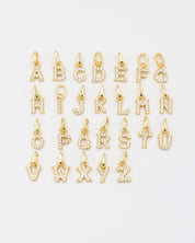 Gold-plated sparkly letter pendants arranged in a complete A-Z display, showcasing their zirconia embellishments.