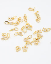 Scattered gold-plated letter pendants, each adorned with sparkling zirconia stones, perfect for a personalized look.