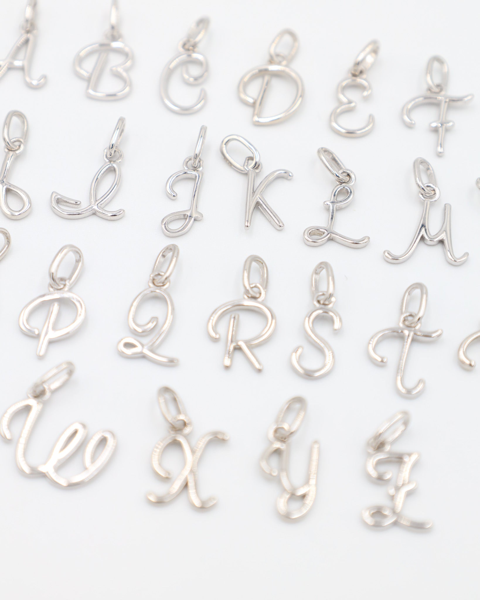 Rhodium plated 925 sterling silver letter curve pendants from A to Z, displayed in a grid layout.