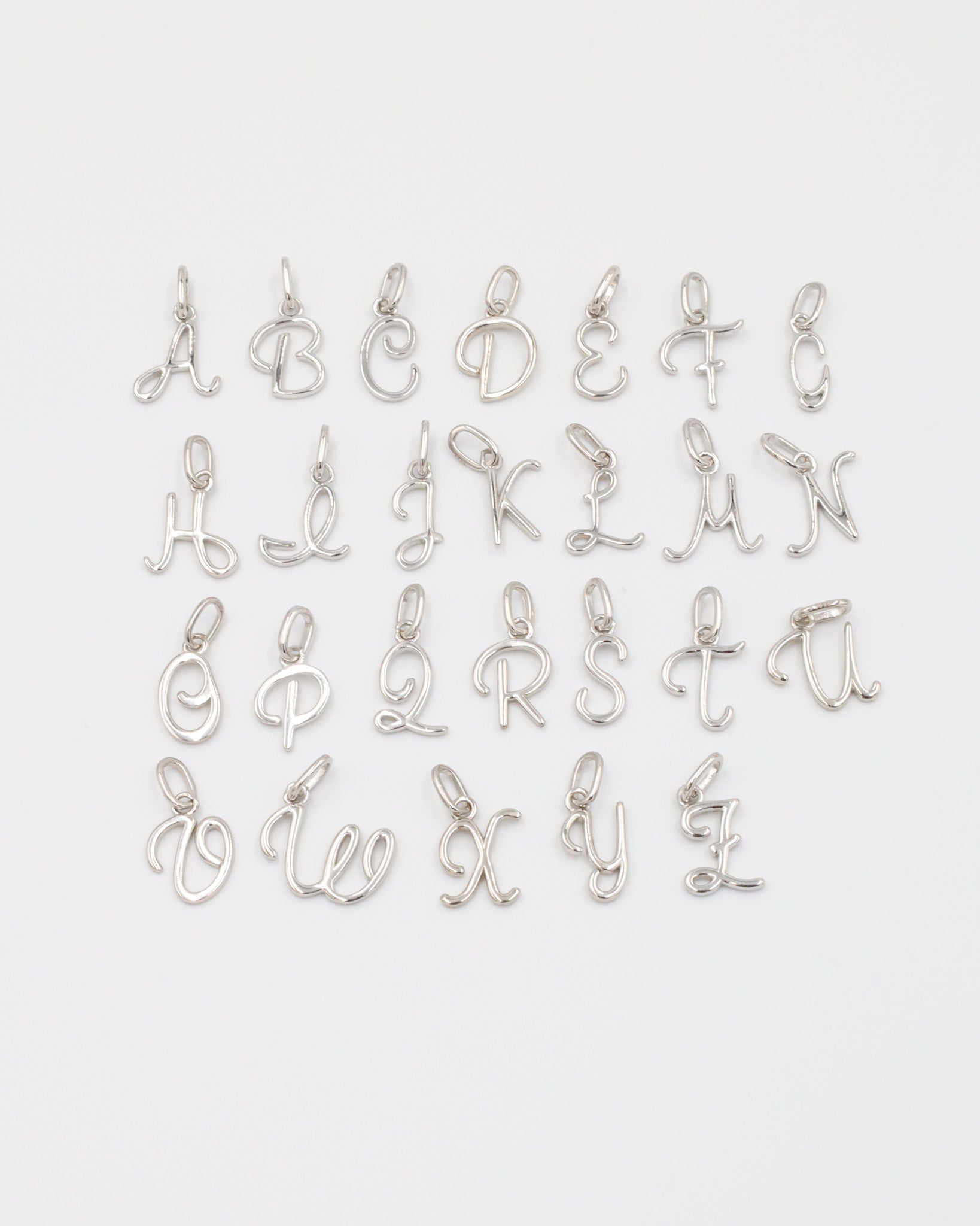 Full set of rhodium plated 925 sterling silver letter curve pendants displayed in alphabetical order.
