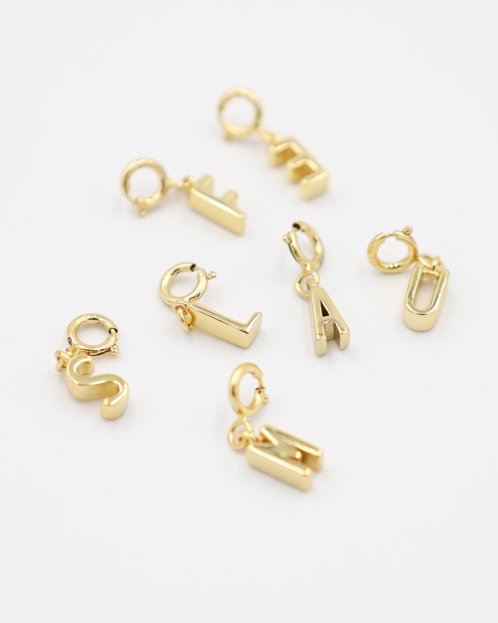 Gold-plated letter pendants with clasp, made from 925 sterling silver, displayed together in various letter designs. Each pendant can be easily attached to any chain necklace.