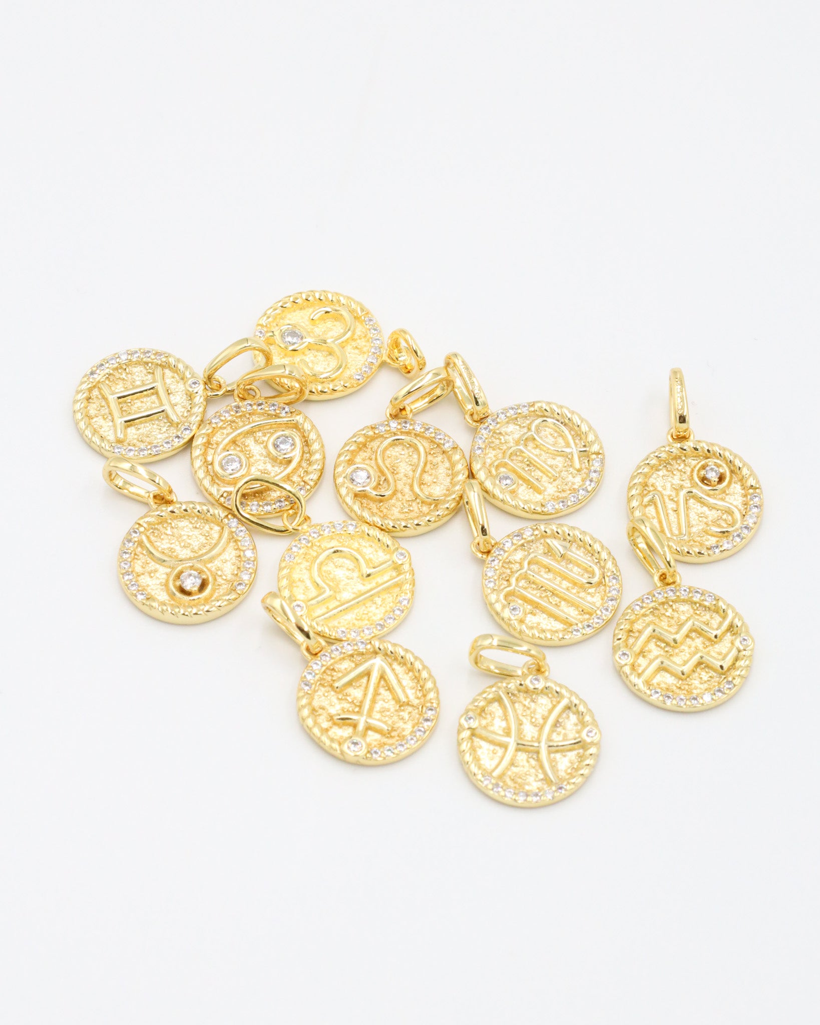 Assorted zodiac symbol pendants in gold-plated sterling silver featuring zirconia accents.