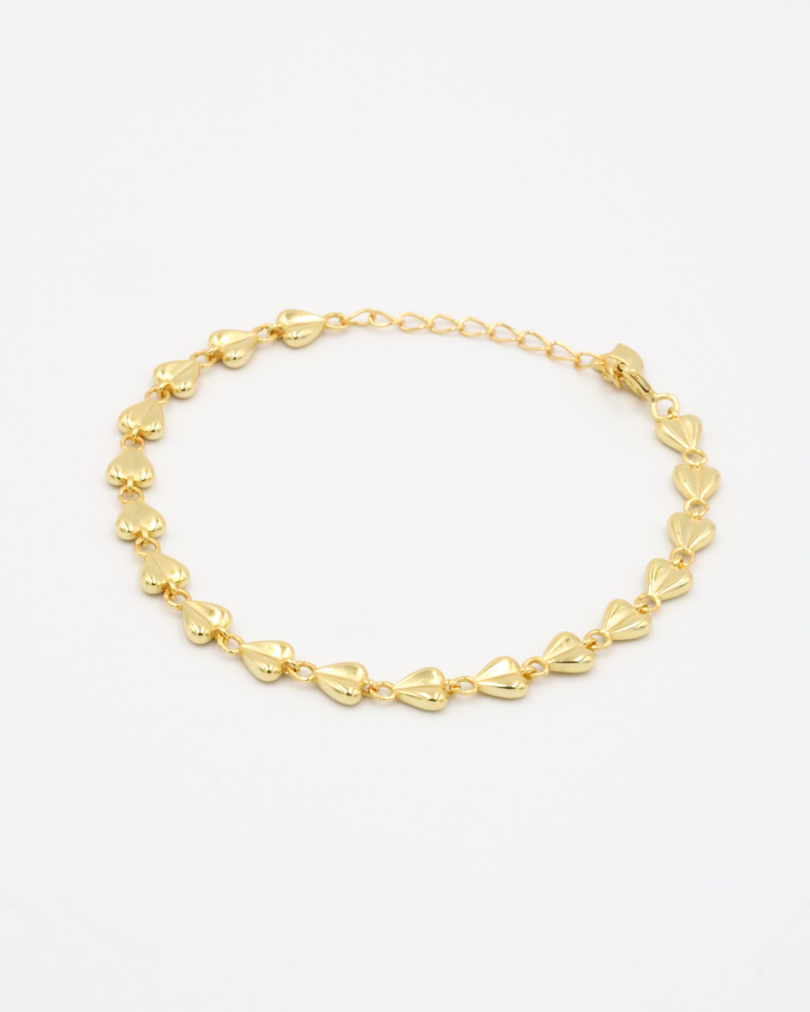 A gold bracelet with a heart-shaped pattern on a white background