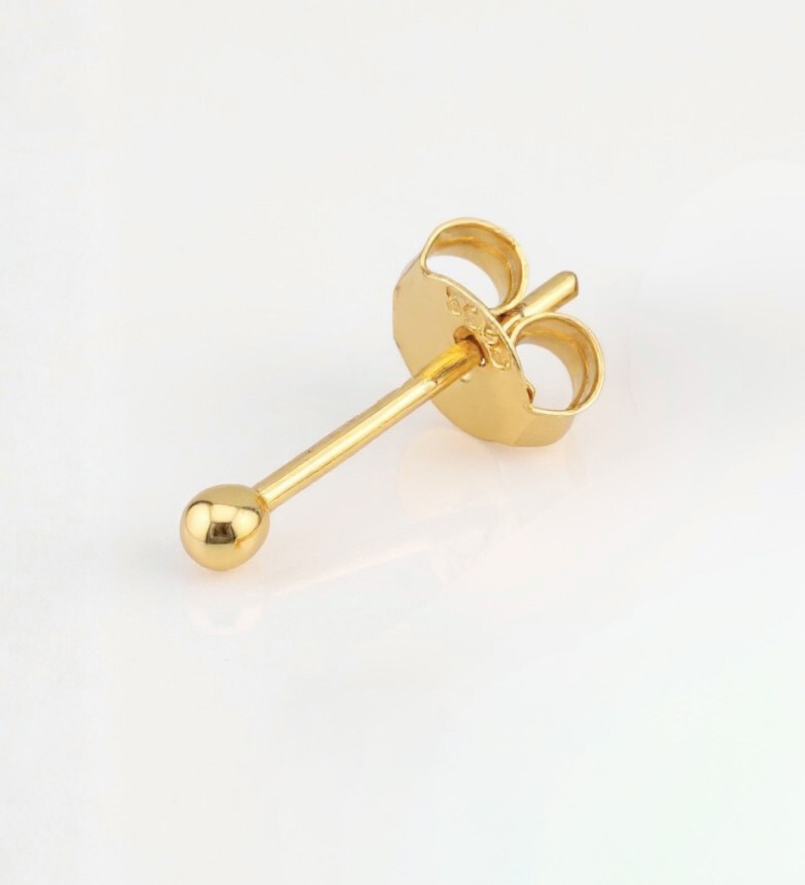 Gold earring on a light gray background