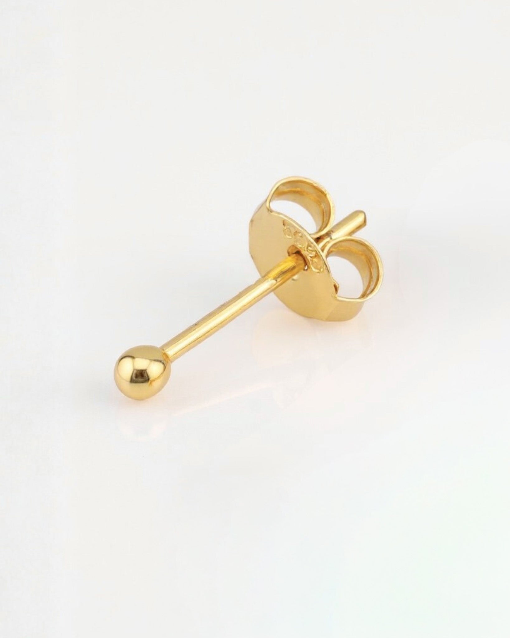 Gold earring on a light gray background