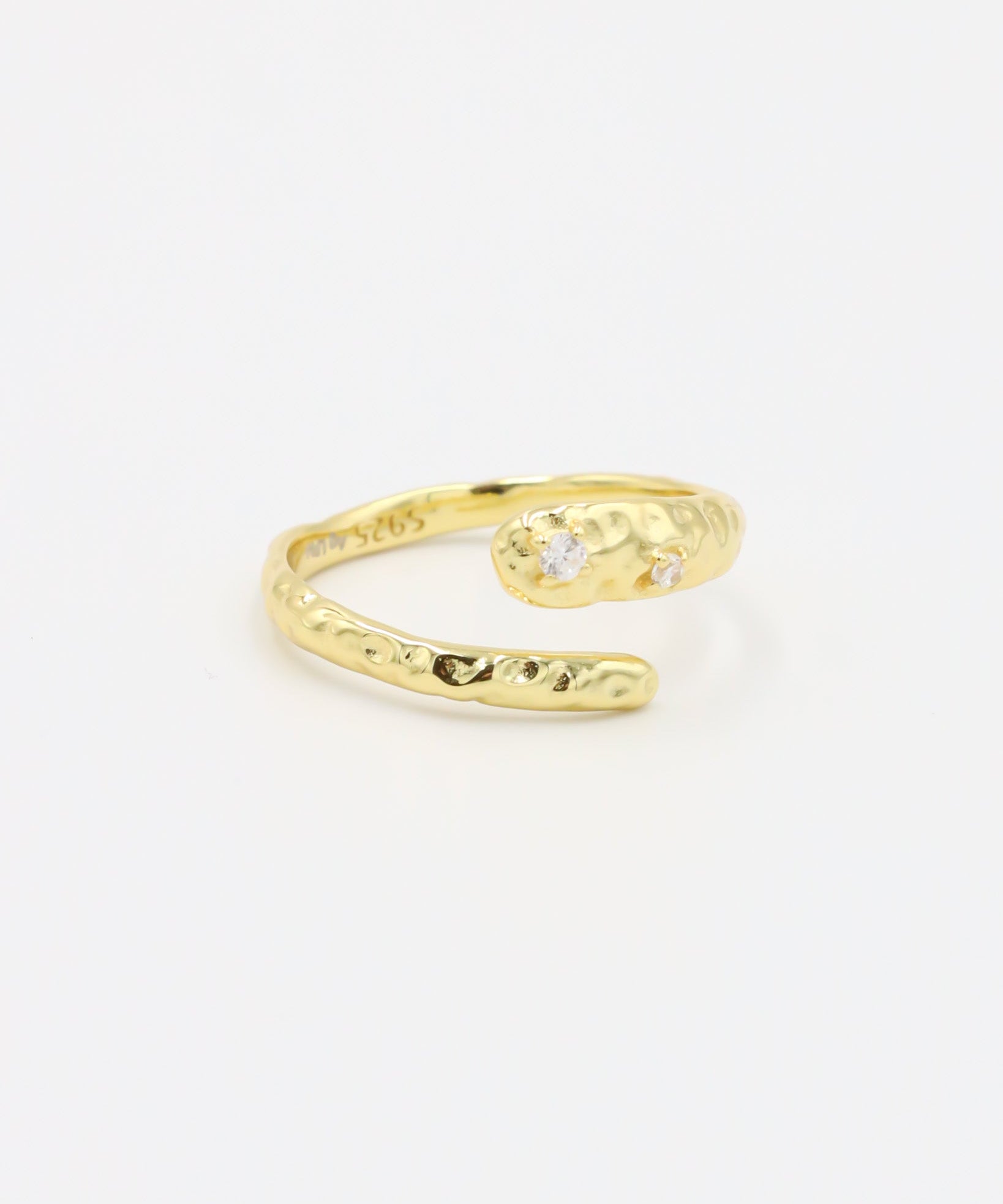 Close-up of an open gold-plated 925 sterling silver ring with a hammered texture and three delicate zirconia stones, handcrafted and photographed on a white background – minimalist Swiss jewelry design.
