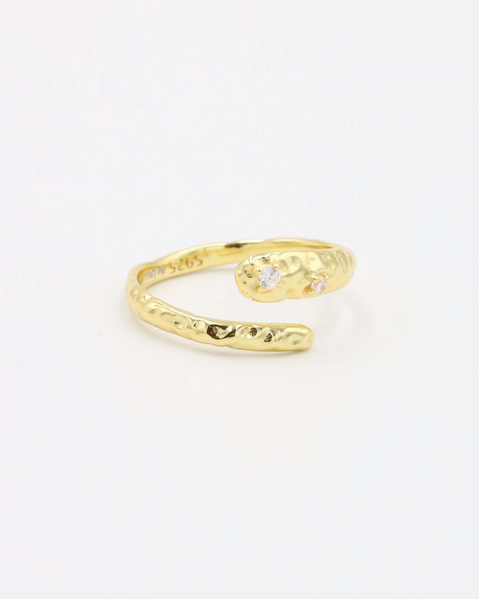 Close-up of an open gold-plated 925 sterling silver ring with a hammered texture and three delicate zirconia stones, handcrafted and photographed on a white background – minimalist Swiss jewelry design.