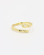 Close-up of an open gold-plated 925 sterling silver ring with a hammered texture and three delicate zirconia stones, handcrafted and photographed on a white background – minimalist Swiss jewelry design.