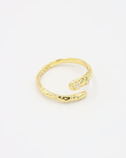 Close-up of an open gold-plated 925 sterling silver ring with a hammered texture and three delicate zirconia stones, handcrafted and photographed on a white background – minimalist Swiss jewelry design.