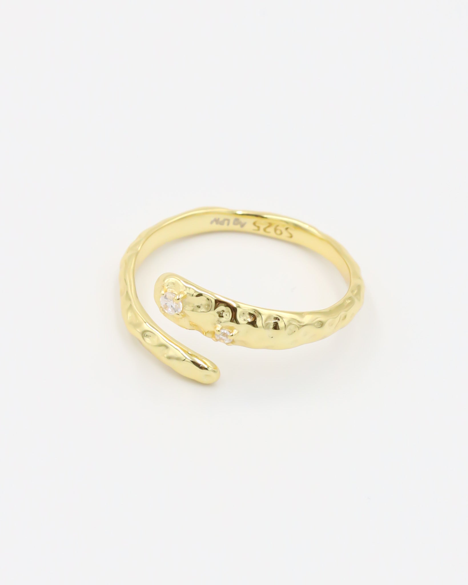 Close-up of an open gold-plated 925 sterling silver ring with a hammered texture and three delicate zirconia stones, handcrafted and photographed on a white background – minimalist Swiss jewelry design.