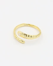 Close-up of an open gold-plated 925 sterling silver ring with a hammered texture and three delicate zirconia stones, handcrafted and photographed on a white background – minimalist Swiss jewelry design.