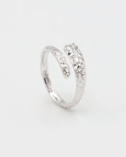 Close-up of an open rhodium-plated 925 sterling silver ring with a hammered texture and three delicate zirconia stones, handcrafted and photographed on a white background – minimalist Swiss jewelry design.