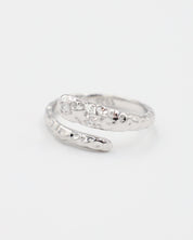 Close-up of an open rhodium-plated 925 sterling silver ring with a hammered texture and three delicate zirconia stones, handcrafted and photographed on a white background – minimalist Swiss jewelry design.
