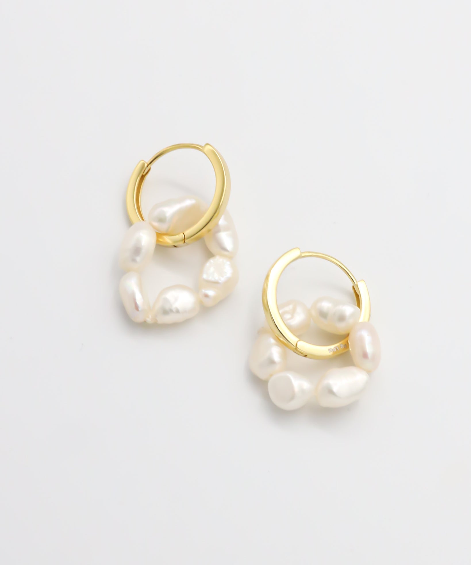 A pair of gold hoop earrings with white pearls attached to them, displayed on a white background.