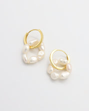 A pair of gold hoop earrings with white pearls attached to them, displayed on a white background.