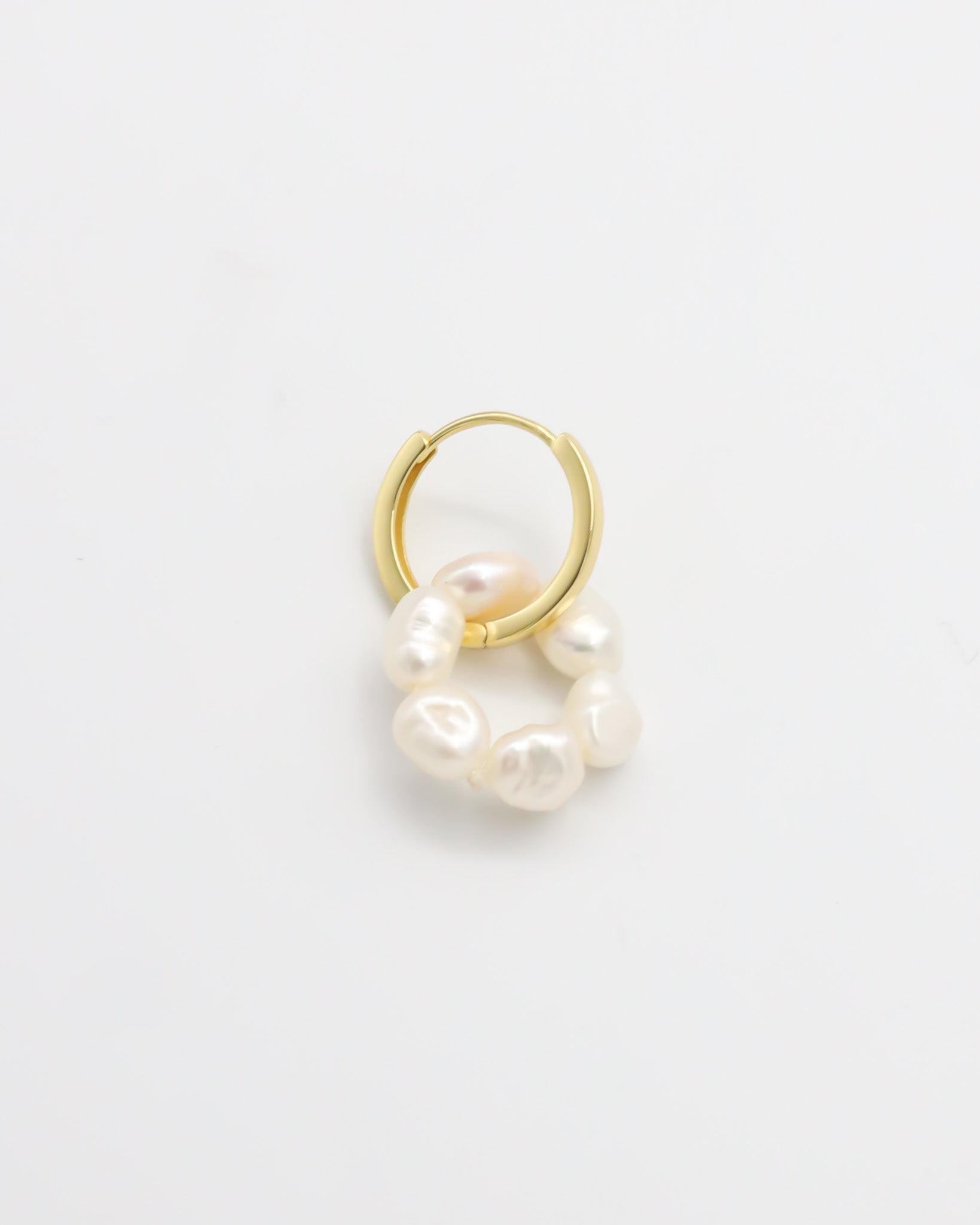 A single gold hoop earring with white pearls attached to it, displayed on a white background.