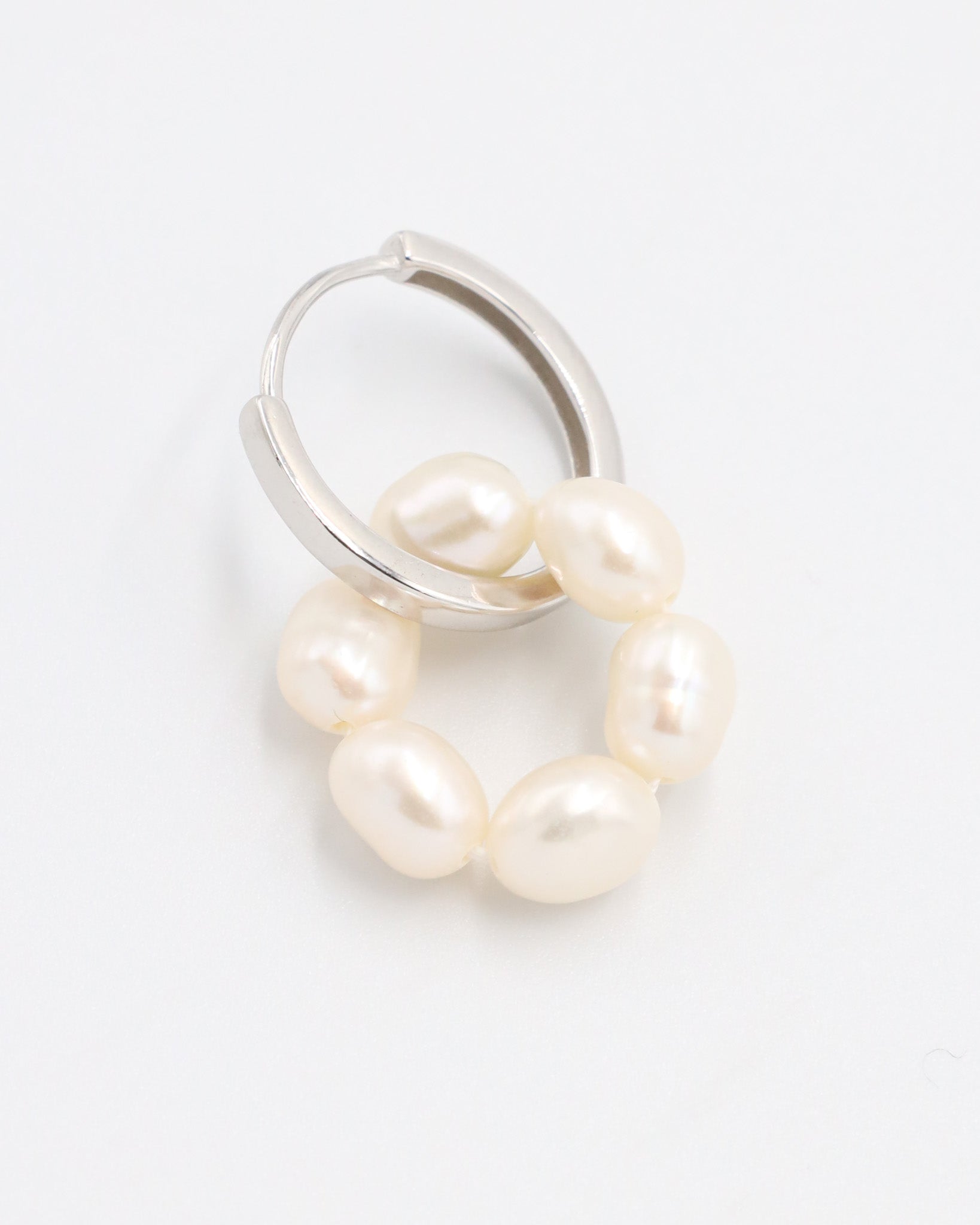 A single silver hoop earring with white pearls attached to it, displayed on a white background.