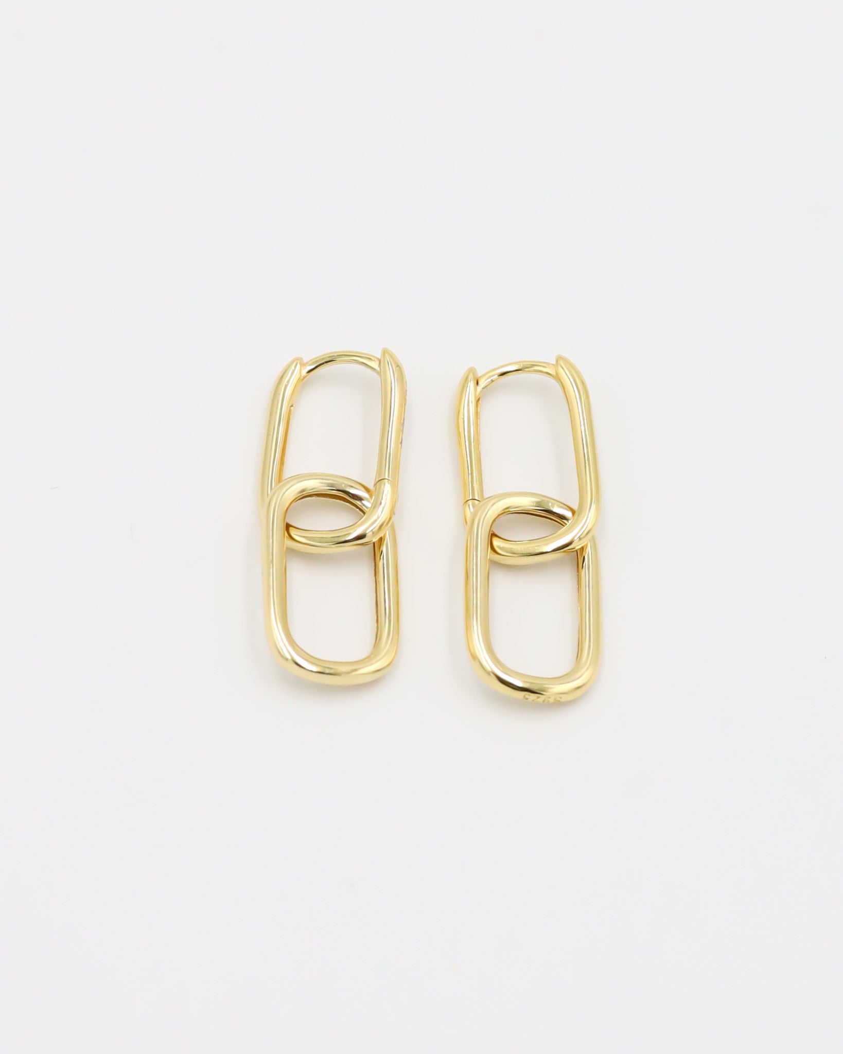 A pair of gold-colored hoop earrings with a hinged clasp, displayed against a white background.