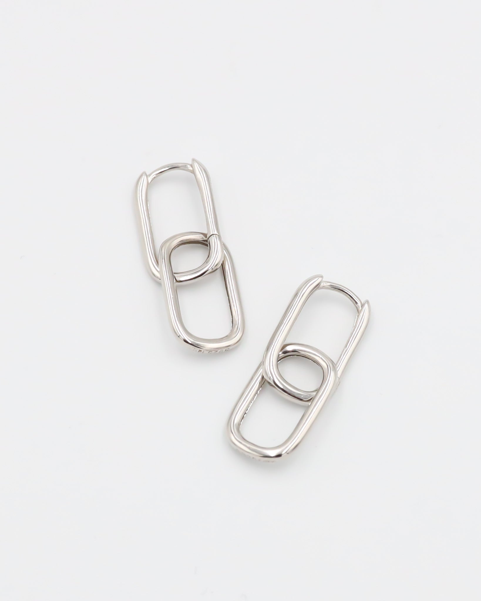 A pair of silver hoop earrings with a hinged clasp, displayed against a white background.