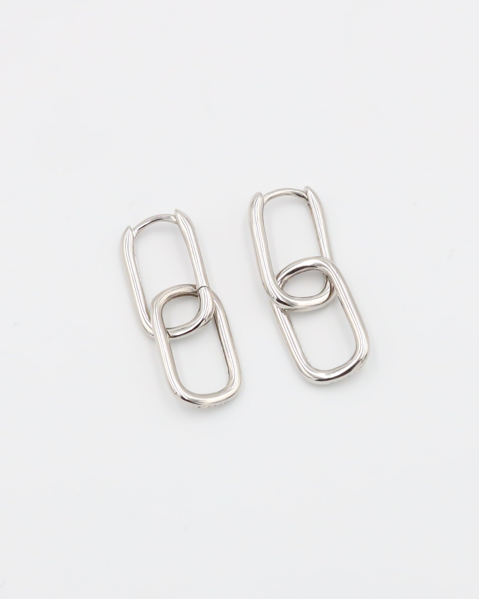 A pair of silver hoop earrings with a hinged clasp, displayed against a white background.