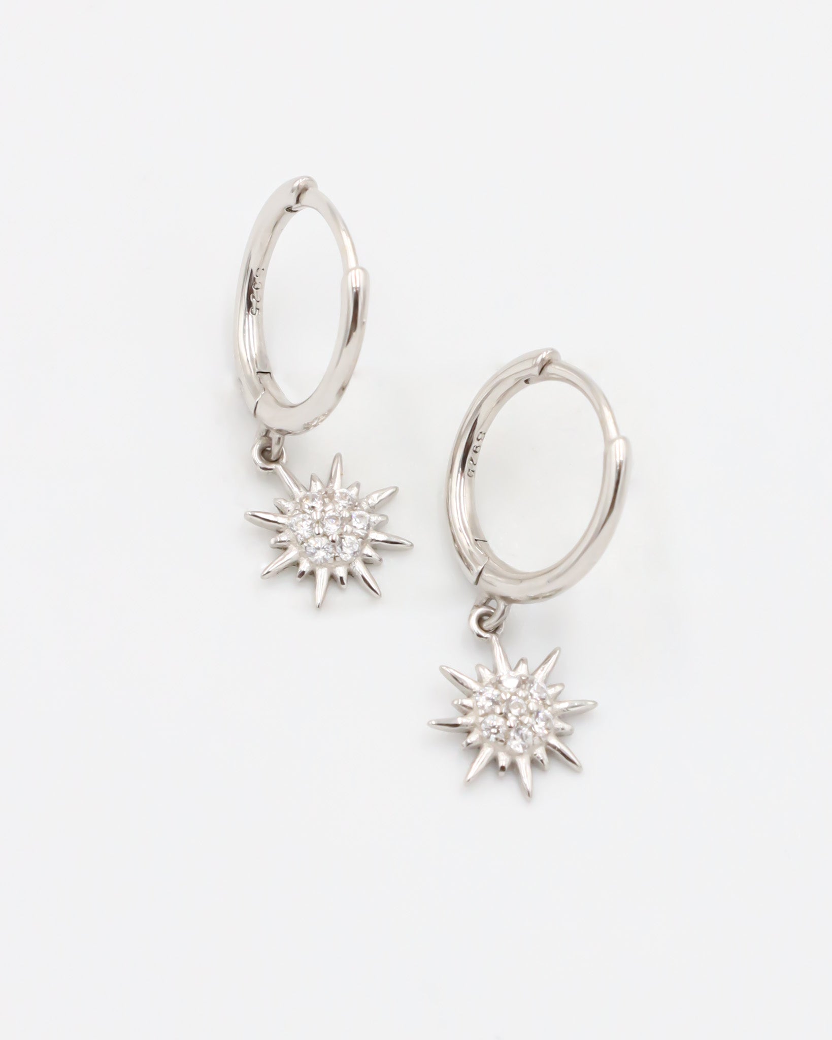 A silver hoop earring with a star-shaped charm attached to it, displayed against a white background.